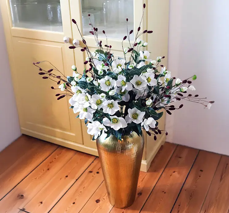 Julerose kunstig blomst af plast i hvid vist i vase med kunstig kvæsurte gren i stuemiljø