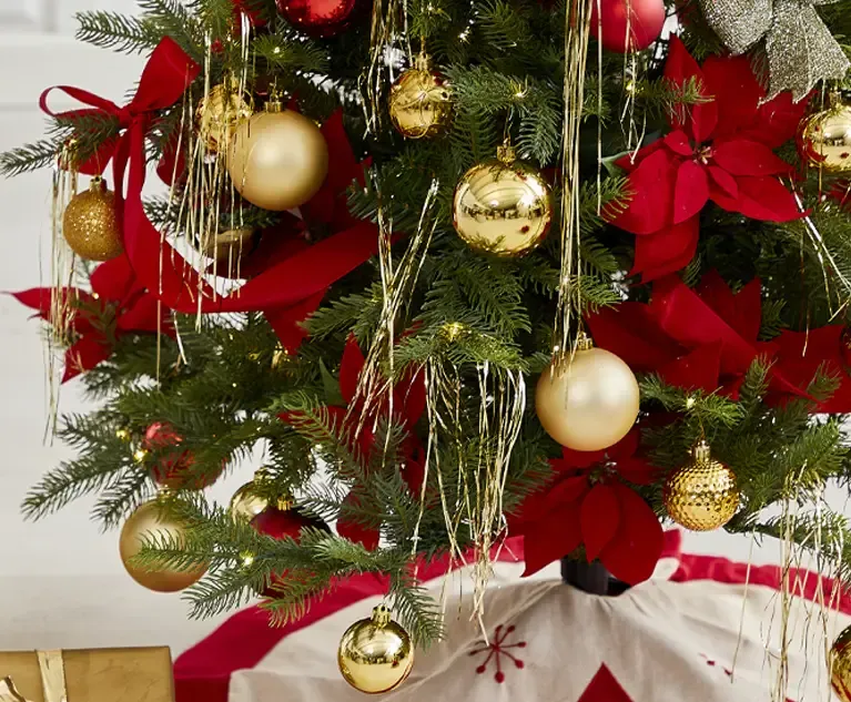 kunstig juletræ med lys og plast julekugler i rød og guld, samt fine kunstige julestjerner