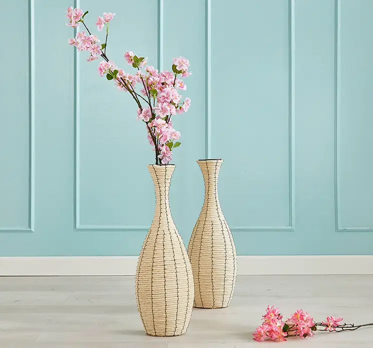 Vase af flettet reb i hvid vist med en kunstig kirsebær blomstergren i stuemiljø