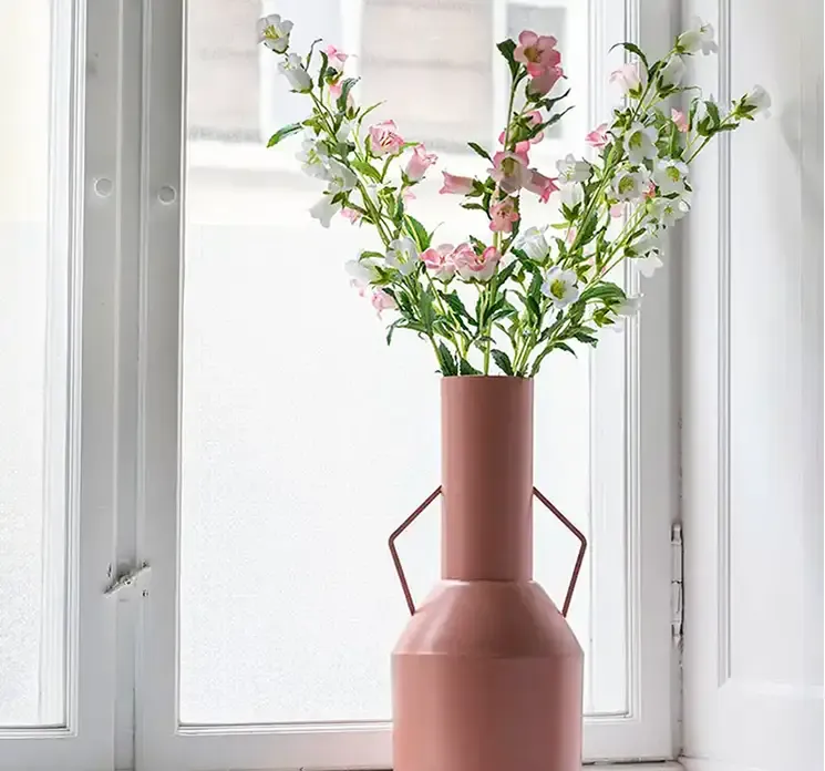 Kunstig klokke blomst af plast i lyserød vist i flot lyserød vase af metal i vindueskarm