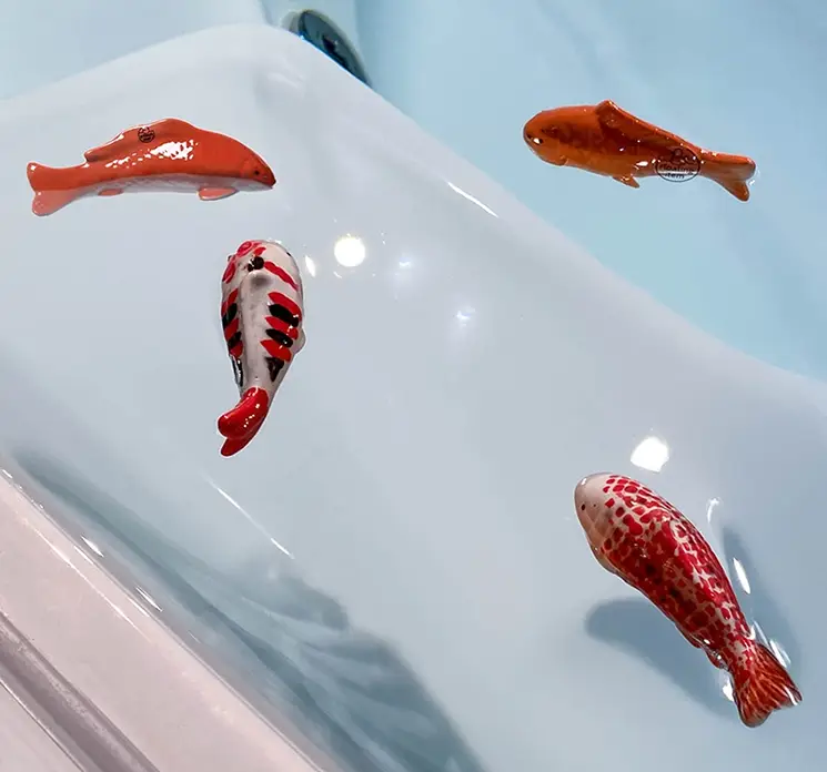 Koi karpe kunstig fisk af porcelæn der kan flyde i hvid og orange vist flydende i badekar med vand
