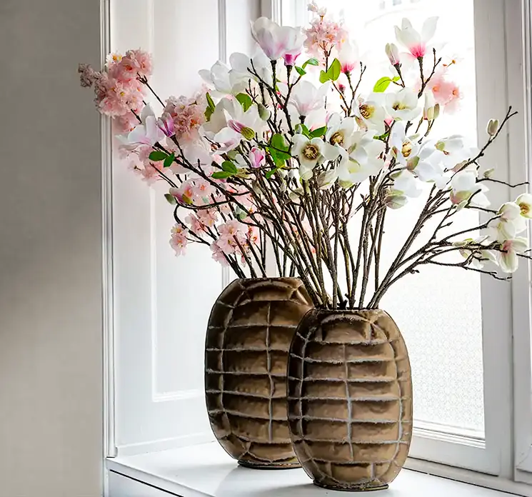 Vaser med skildpadde struktur af metal i bronze look vist med kunstige blomstergrene i vindueskarm