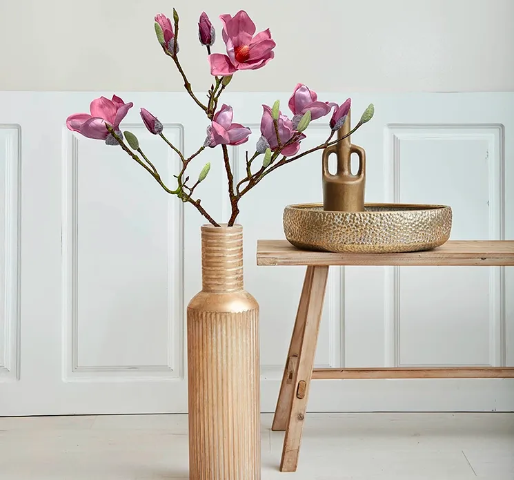kunstig magnolie blomstergren i fuchsia sat i en høj vase af metal i guldfarvet