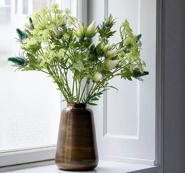 Kunstig dild blomst i hvid vist i vase med andre kunstige blomster i metal vase