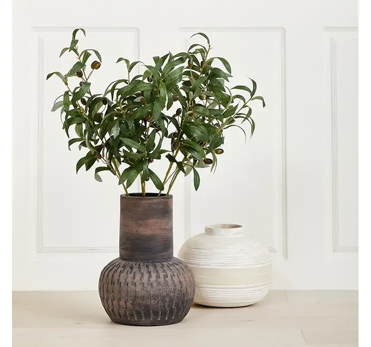 Kunstige olivengrene af plast med sorte oliven vist i terrascotta vase i miljø