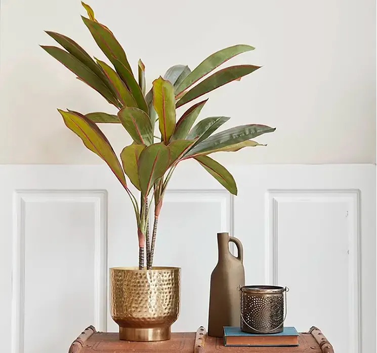 Fyrfadsholder af metal med hank vist i miljø med kunstig plante