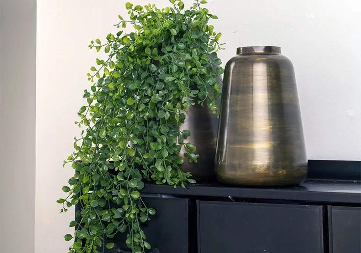 kunstig pilea hængeplante sat i en vase af metal