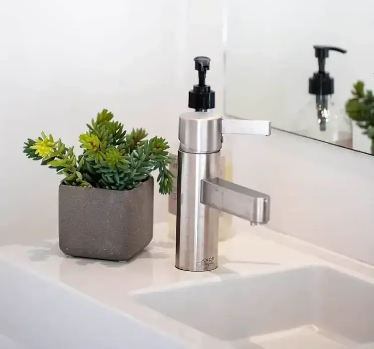 Kunstig sukkulent plante af plast i firkantet krukke vist på håndvask på badeværelse