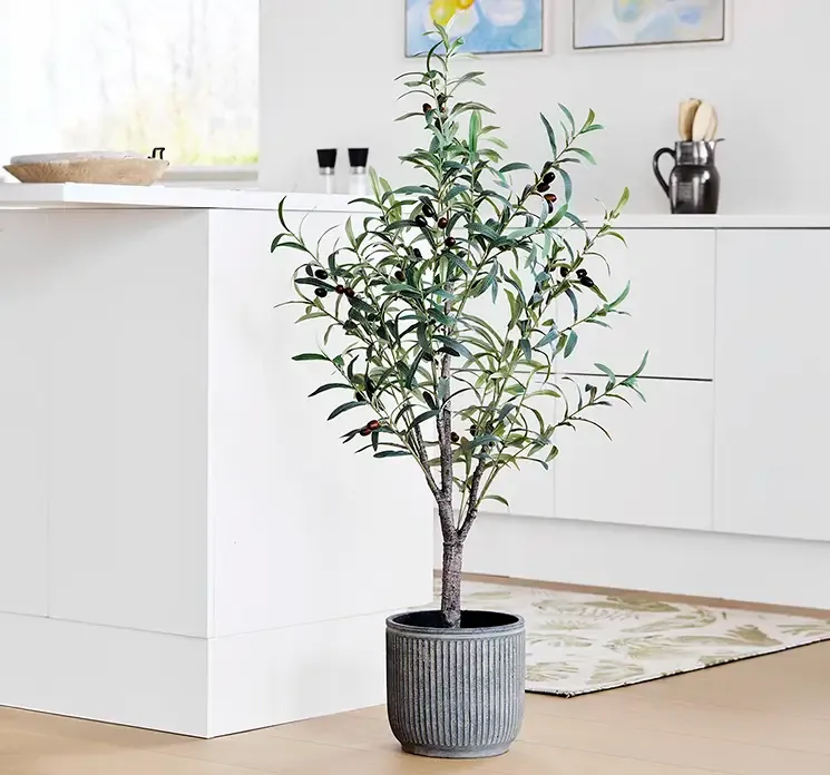 Oliventræ af plast i grøn med kunstige oliven sat i cement potte i køkkenmiljø