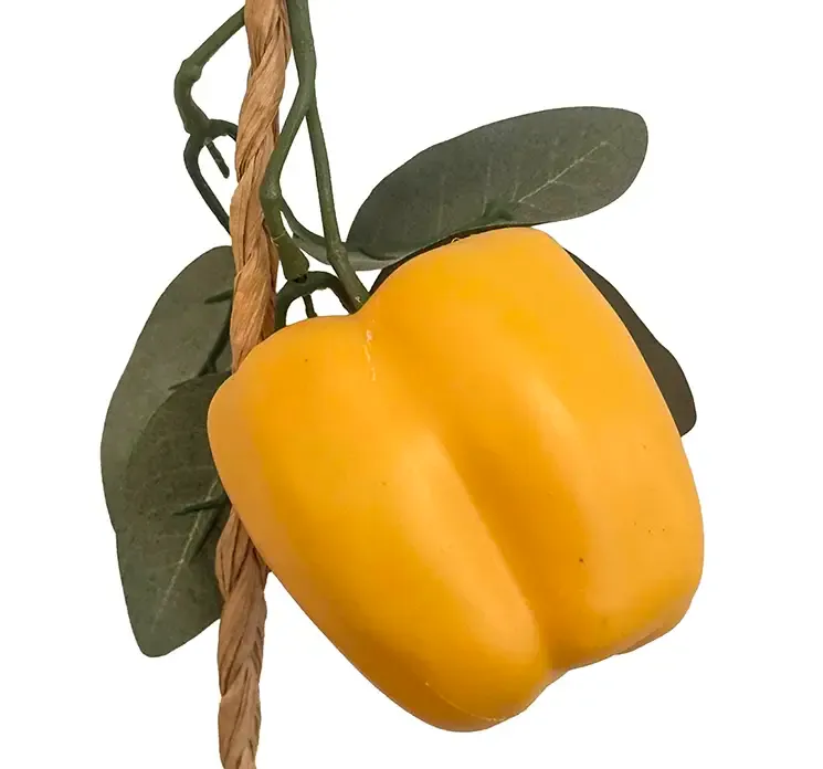 Kunstig peberfrugt i gul på ranke af flettet jute reb closeup