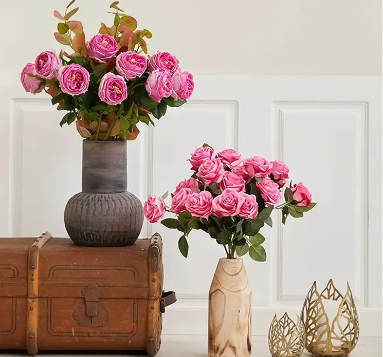 Kunstig og naturtro rose af plast i lyserød vist i terracotta vase i stuemiljø 