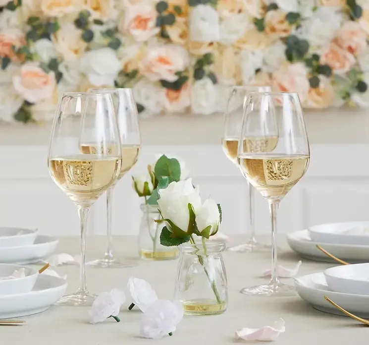 Kunstige små rosenblomster hoveder i hvid vist på et bryllupsdækket bord