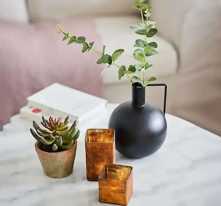 Lysestager af glas i kobberfarvet vist i miljø på sofabord