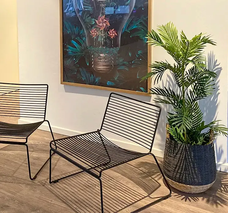 Kunstig palmetræ sat i en fletkurv i kontormiljø