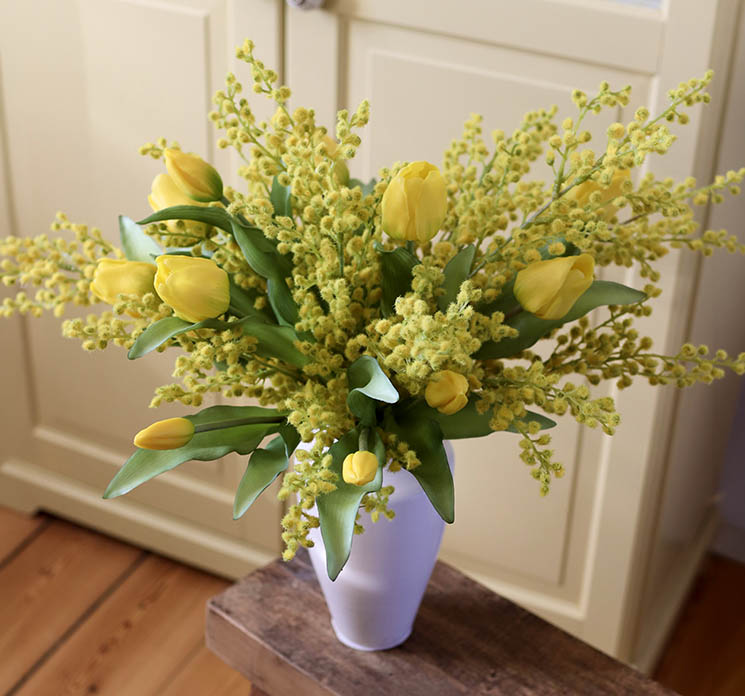 Kunstige tulipaner og mimosa sat sammen i en fin hvid vase i køkkenmiljø