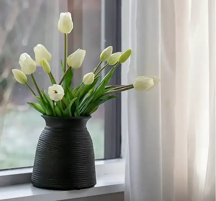 Kunstig tulipanbuket i hvid af plast gummi sat i en vase i vindueskarm