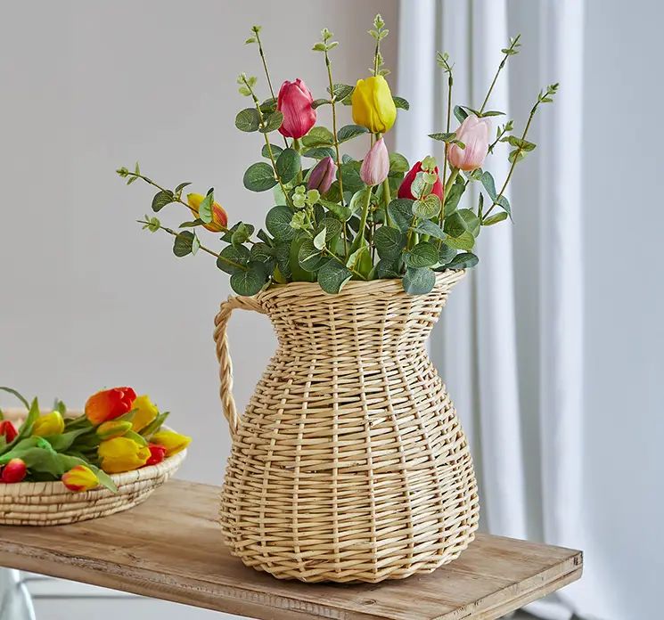 Tulipan buket af kunstig blomster og eukalyptus af plast vist i flettet vase kande i stuemiljø