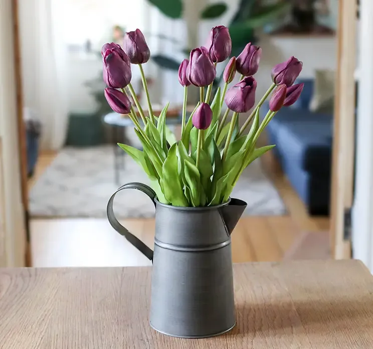 Kunstig tulipan buket i lilla vist i en zink vase formet som en kande i stuemiljø