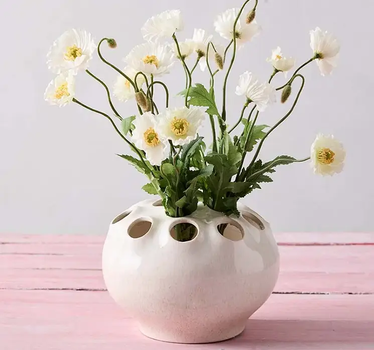 Valmuebuket af kunstige blomster af plast i hvid vist i ikebana vase med flere huller