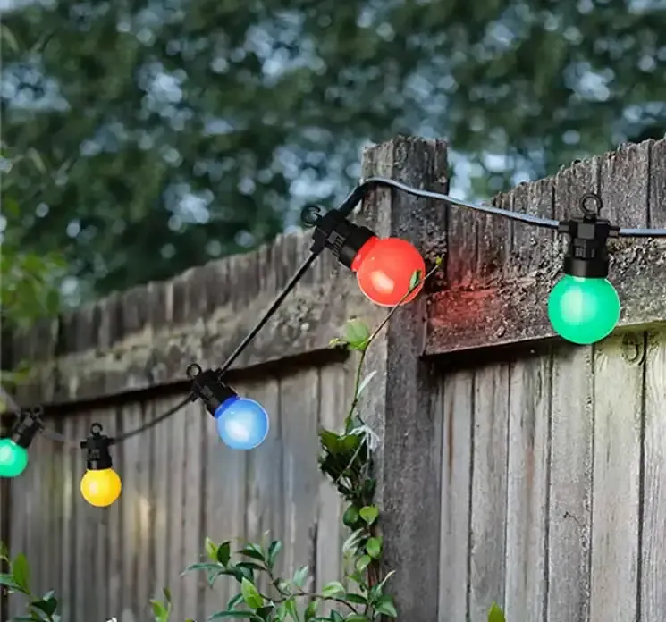 Lyskæde med multifarvede pærer og sort ledning vist i have miljø