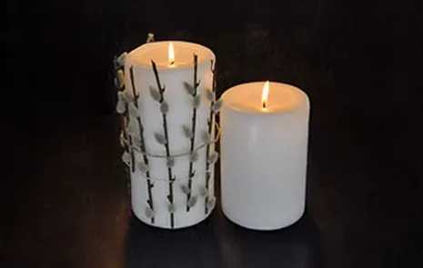 2 lys hvor den ene har fået bundet kunstige gæslingegrene omkring