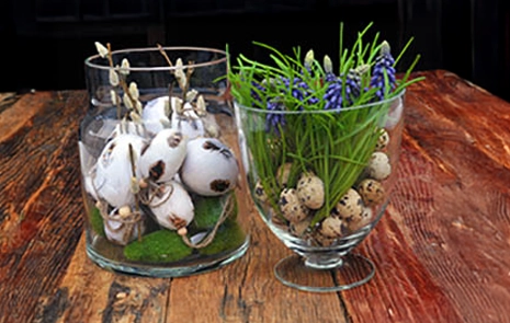 Påskeæg i to forskellige glasvaser med kunstige gæslingegrene og perlehyacinter