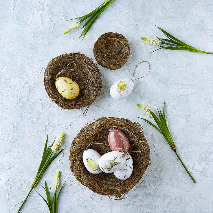 Påskeæg af plast og små fuglereder samt kunstige perlehyacinter på en bordplade