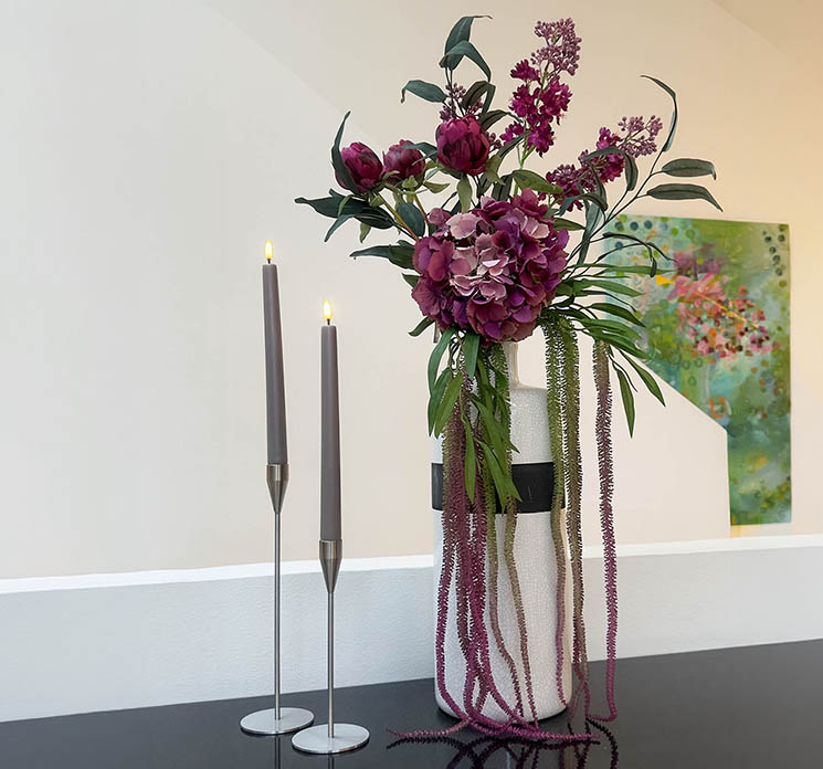 Buket af kunstig hortensia, pæoner, syren, amarant og eukalyptusgren sat i porcelænsvase i køkkenmiljø
