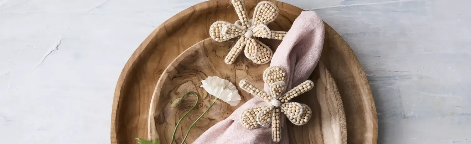 Små fine serviet ringe med med blomster lavet af træperler lagt på træfade