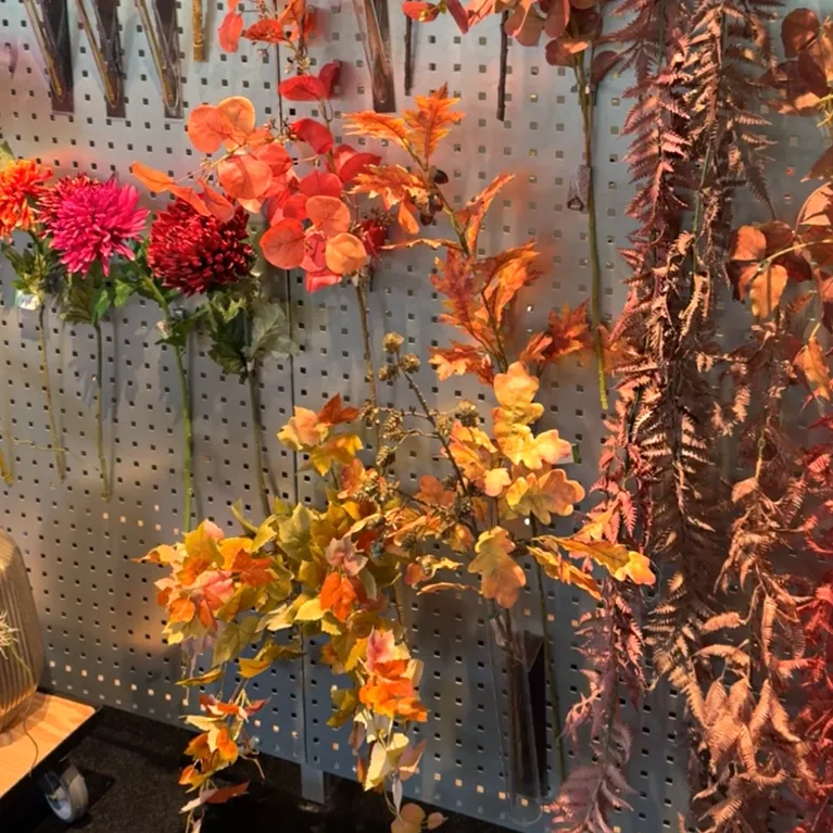 kunstige efterårsgrene, efterårs ranker og blomster vist på væg i showroom