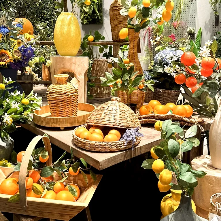 Kunstige citrontræer og grene, samt appelsiner sat i forskellige flotte trækrukker og vaser