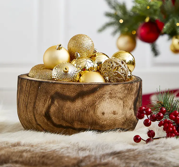 Skål af træ rund vist med julekugler af plast i guldfarvet i julemiljø