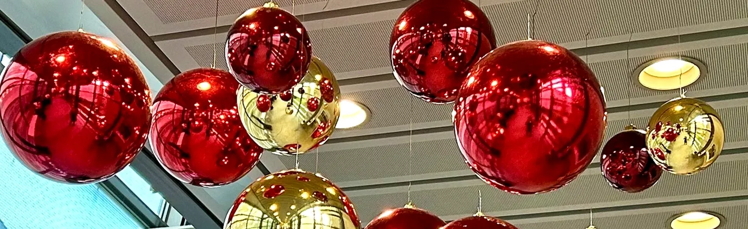 store plast julekugler i rød og guld der hænger ned fra loft