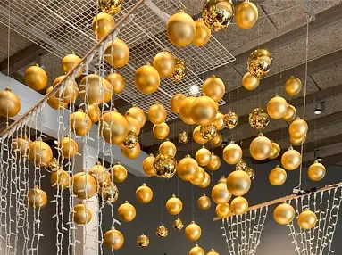 store plast julekugler i guld og forskellige størrelser hænger ned fra loftet 