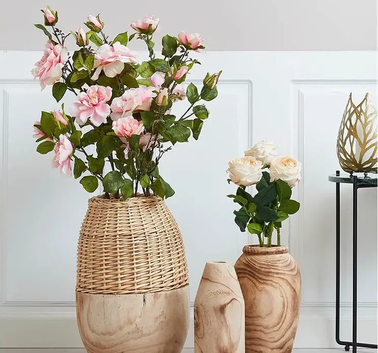 Kunstig og naturtro rose af plast i fersken farve vist i miljø med andre kunstige roser