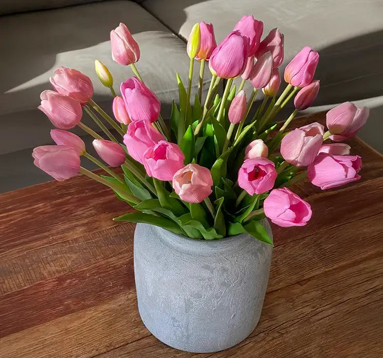 Kunstige tulipan buketter i lyserøde farver sat i en rustik vase på sofabord