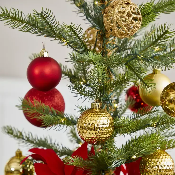 Kunstigt juletræ med plast julekugler i rød og guld