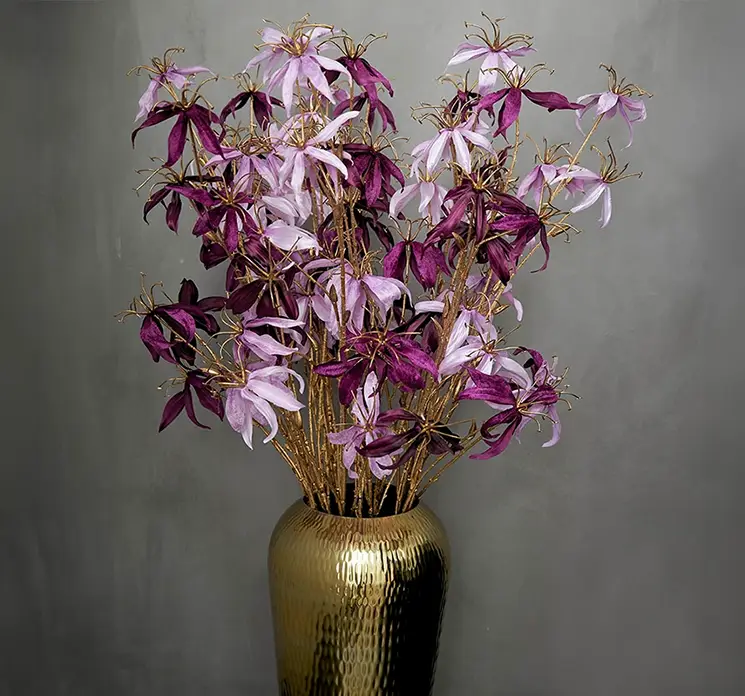 Klatrelilje kunstig blomst af plast i lilla og guldfarvet vist i guld vase med klatreliljer i lyselilla