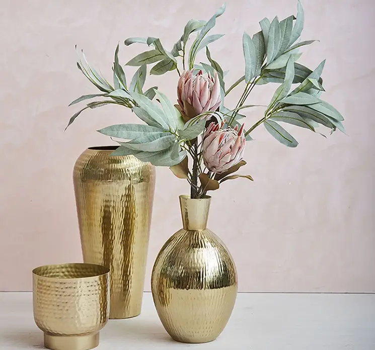 Protea kunstig blomst af plast i fersken farvet vist sammen med kunstig eukalyptus gren i flot guld vase
