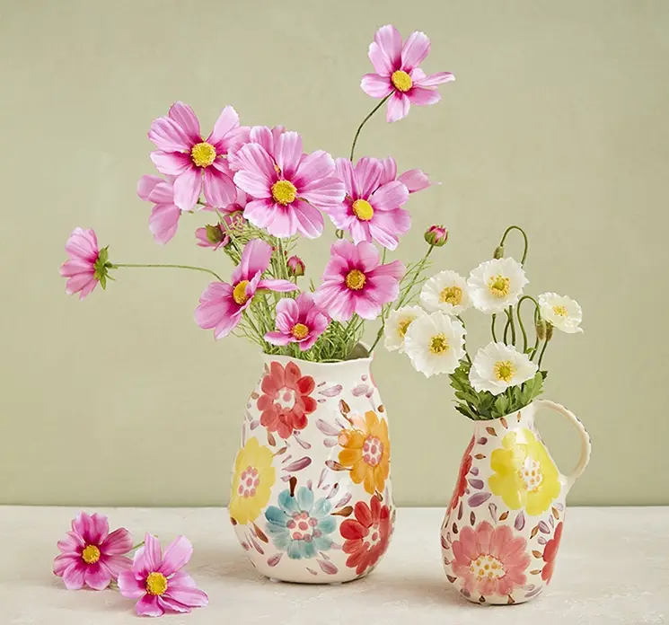 Vase af håndlavet keramik med hank og påmalede blomster i multifarver vist med kunstige valmue og stolt kavaler blomster