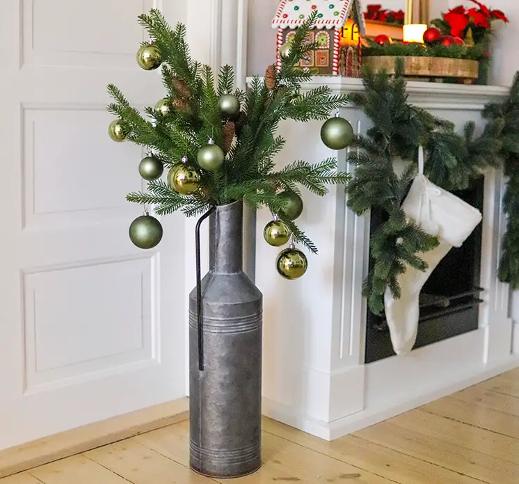 Vase kande af zink vist med kunstig gran gren med kogler i julemiljø
