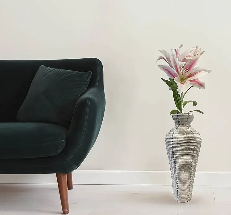 Lilje på stilk kunstig blomst af plast i lyserød og hvid vist i flettet vase i stuemiljø