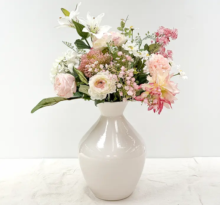 Vase af jern i hvid vist med en færdig buket på et bord