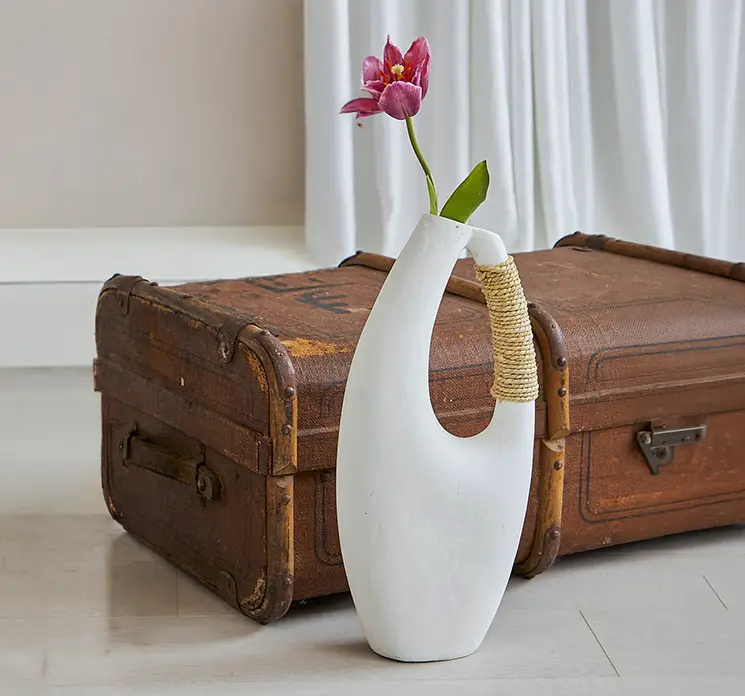 Vase af papmache i off white med hank og reb detalje vist med en enkelt kunstig tulipan i stuemiljø