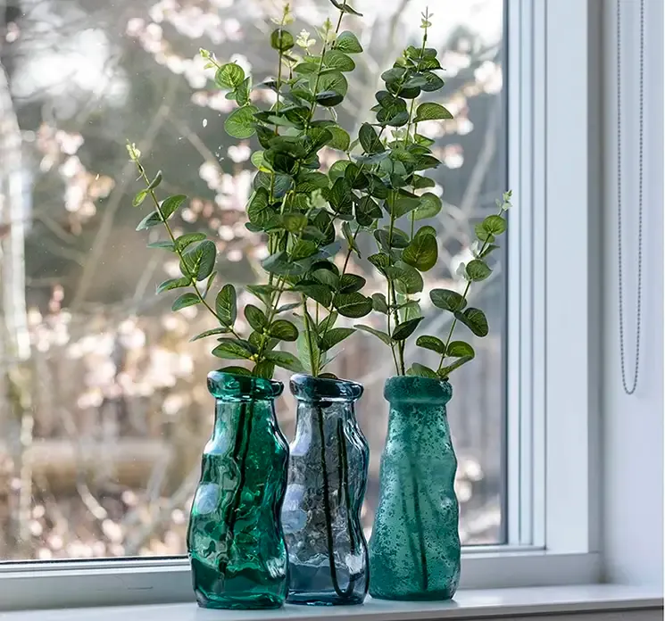 Vase simplicity af glas i grøn vist i vindueskarm med tre andre vaser og kunstig eukalyptus grene