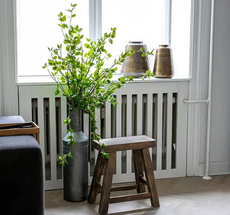 vase kande i grå zink i stuemiljø med kunstige grønne grene