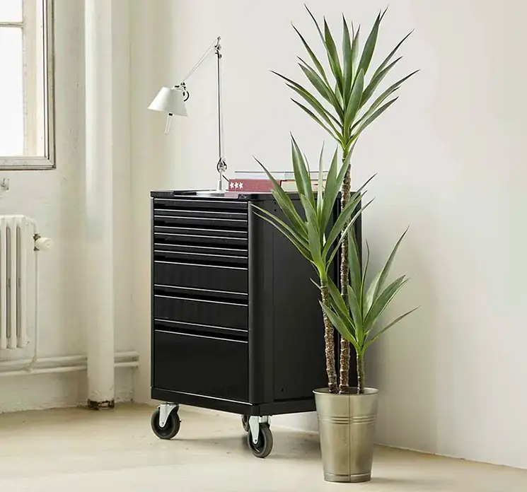 Vase af zink i grå vist med en kunstig plante i kontormiljø